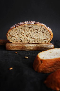Koyu bir arka planda tahtadan parçalar kesmek için taze tahıl ekmeği.