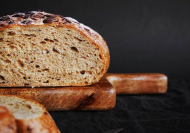 Koyu bir arka planda tahtadan parçalar kesmek için taze tahıl ekmeği.