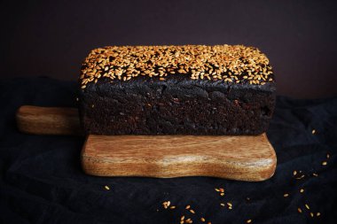 Tahta bir tahta üzerinde tahıllı taze kahverengi ekmek ve susam.