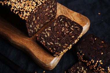 Tahta bir tahta üzerinde tahıllı taze kahverengi ekmek ve susam.