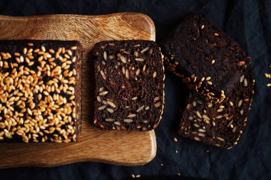 Tahta bir tahta üzerinde tahıllı taze kahverengi ekmek ve susam.