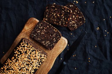 Tahta bir tahta üzerinde tahıllı taze kahverengi ekmek ve susam.