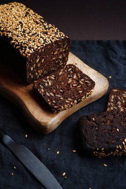 Tahta bir tahta üzerinde tahıllı taze kahverengi ekmek ve susam.