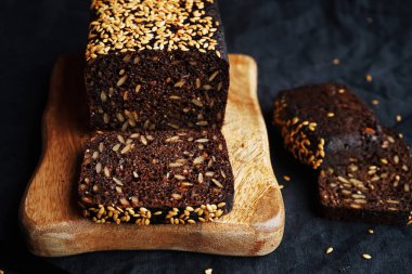 Tahta bir tahta üzerinde tahıllı taze kahverengi ekmek ve susam.