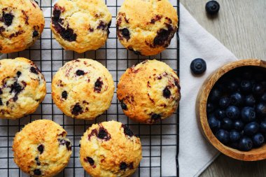 Metal örgü tepside yaban mersinli vanilyalı kek ve gri arka planda yabanmersinli pamuk havlu.