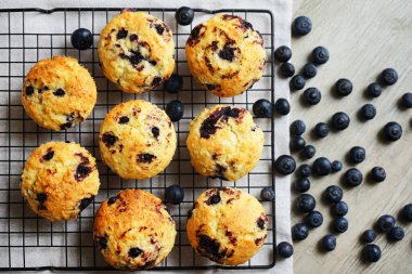 Metal örgü tepside yaban mersinli vanilyalı kek ve gri arka planda yabanmersinli pamuk havlu.