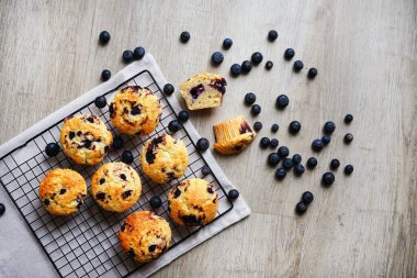 Metal örgü tepside yaban mersinli vanilyalı kek ve gri arka planda yabanmersinli pamuk havlu.