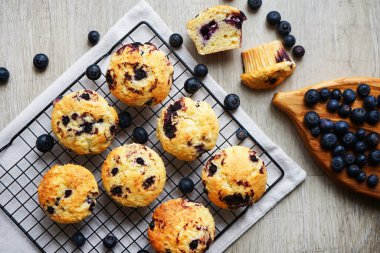 Metal örgü tepside yaban mersinli vanilyalı kek ve gri arka planda yabanmersinli pamuk havlu.