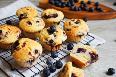 Yaban mersinli vanilyalı çörekler metal ağ tepsisine yakın çekim ve gri arka planda pamuk havlu.