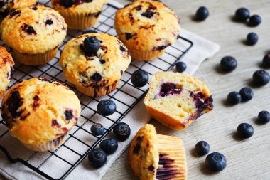 Yaban mersinli vanilyalı çörekler metal ağ tepsisine yakın çekim ve gri arka planda pamuk havlu.