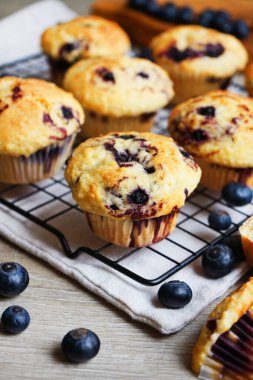 Yaban mersinli vanilyalı çörekler metal ağ tepsisine yakın çekim ve gri arka planda pamuk havlu.