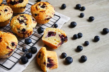 Metal örgü tepside yaban mersinli vanilyalı kek ve gri arka planda yabanmersinli pamuk havlu.