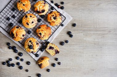 Metal örgü tepside yaban mersinli vanilyalı kek ve gri arka planda yabanmersinli pamuk havlu.