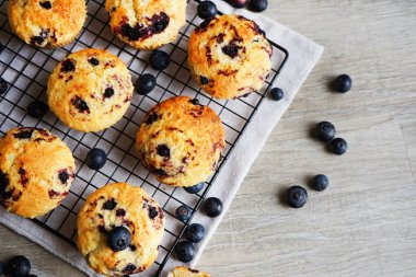 Metal örgü tepside yaban mersinli vanilyalı kek ve gri arka planda yabanmersinli pamuk havlu.