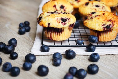Yaban mersinli vanilyalı çörekler metal ağ tepsisine yakın çekim ve gri arka planda pamuk havlu.