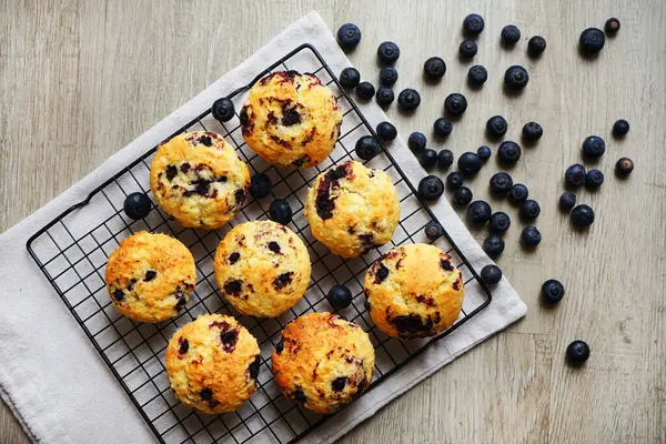 Metal örgü tepside yaban mersinli vanilyalı kek ve gri arka planda yabanmersinli pamuk havlu.