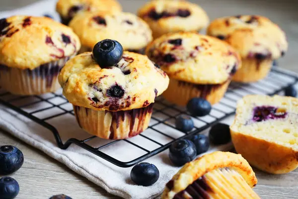 Yaban mersinli vanilyalı çörekler metal ağ tepsisine yakın çekim ve gri arka planda pamuk havlu.