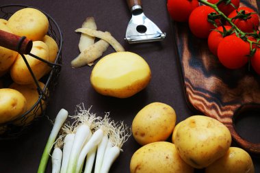 Taze domates, patates ve yeşil soğan. Arka planda sebze soyacağı yanında.