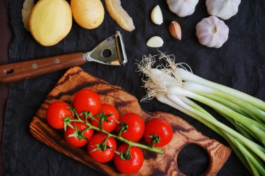Taze domates, patates, yeşil soğan ve sarımsak. Arka planda sebze soyacağı yanında.