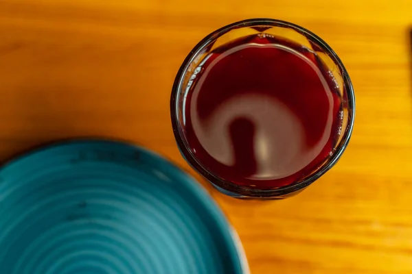 A glass with a red drink and a plate standing on the table top view close-up