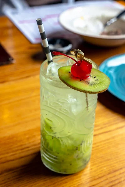 Yazlık yeşil kokteyl, kivi ve kirazlı kamışlı bardak.