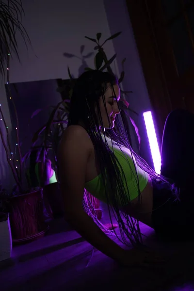 Loş ışıklı bir odada uzun saçlı ince bir kız.