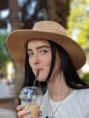 Kız soğuk bir içecekle kendini sıcaktan korur.