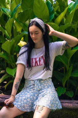 Güzel bir kız egzotik bitkilerin arka planında gelişigüzel poz veriyor.