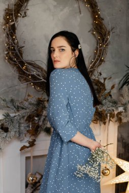 Zarif elbiseli bir esmer stüdyoda poz veriyor.