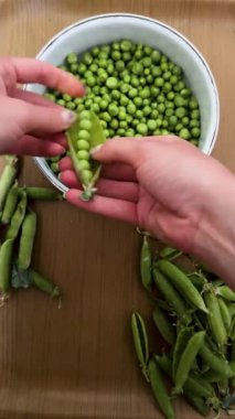 Yeşil bezelye kabuklarını soyan eller