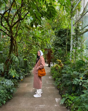  Botanik bahçesinde ceketli bir kadın.