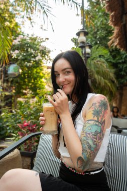 Kahve terasında dövmesi olan güzel genç bir kadın.