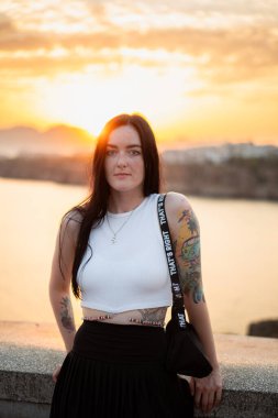 Arkasında günbatımı olan bir kadının portresi.