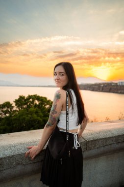 Genç kız gün batımında sahilde poz veriyor.