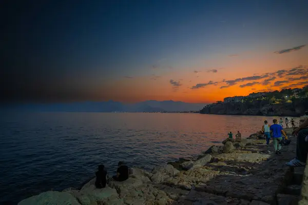 Akdeniz 'de gün batımında kıyıda insanlar var.