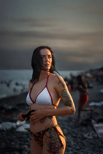 Gün batımında sahilde mayo giymiş dramatik seksi genç bir kadın.