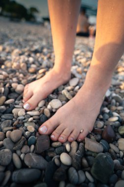 Çakıl taşlı sahilde çıplak ayakla, taş masajın tadını çıkarıyorum.