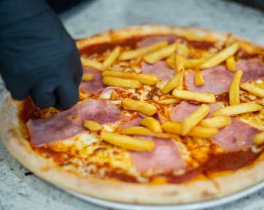 Lezzetli İtalyan pizzası, patates kızartması ve siyah masadaki ahşap tepside pastırma dilimleri. Yüksek kalite fotoğraf