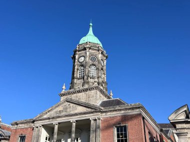Dublin Kalesi 'nin saat kulesi kendine özgü yeşil kubbesi ve saat yüzüyle dağınık bulutlu mavi gökyüzüne karşı dimdik ayakta duruyor. Yüksek kalite fotoğraf