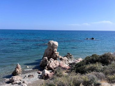 Akdeniz suyunun Afrodit Körfezi 'ndeki Taş Kayalıklı Afrodit Sahili, güneşli arka planda mavi gökyüzü, Kıbrıs Rum Kesimi Petra tu Romiou. Yüksek kalite fotoğraf