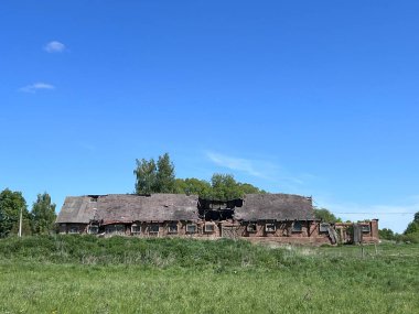 Litvanya 'nın terk edilmiş köyündeki sığır ya da domuz çiftliğine bakın. Arazi, binalar, mavi gökyüzü ve güneşli bir günde bulutlar. Yüksek kalite fotoğraf