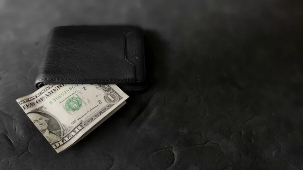 stock image wallet and 1 dollar bill on black background.