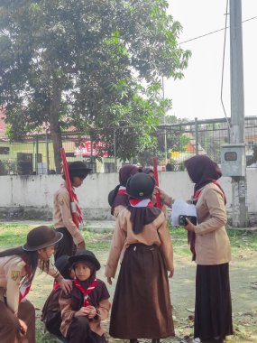 Bandung, Endonezya - 5 Ağustos 2023: Kırmızı ve beyaz başörtüsü ve kravat takan bir grup izci öğrencinin portresi.