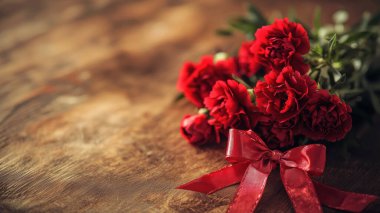 Kırmızı fiyonklu güzel bir karanfil buketi, Sevgililer Günü için mükemmel, fotokopi uzayı ile doğal ışıkta yakalanmış.