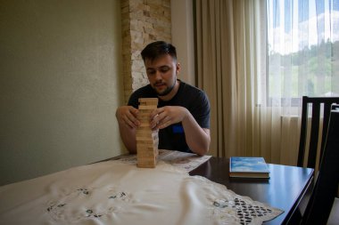 Siyah tişörtlü bir adam Jenga bloklarını ayarlıyor.