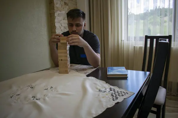 Siyah çoraplı bir adam toplanmış bir binadan ahşap bir fırça çıkararak Jeng 'de bir masa çalar.