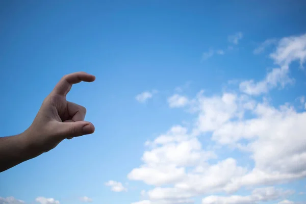 stock image Human hand with index finger and thumb open. Depicted against the background of a blue cloudy sky