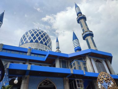 Cami 'nin mavi kubbesinin arka planı gökyüzü ve bulutlardan oluşuyor.