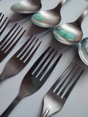 Beyaz arkaplanda birkaç kaşık ve çatal izole edilmiş.