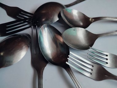 Beyaz arkaplanda birkaç kaşık ve çatal izole edilmiş.